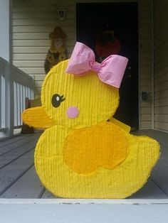 a paper mache duck with a pink bow on it's head sitting in front of a door