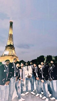 a group of men standing next to each other in front of the eiffel tower