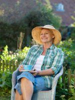 an older woman sitting in a chair holding a cup