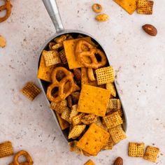 a spoon filled with cheetos and pretzels on top of a table