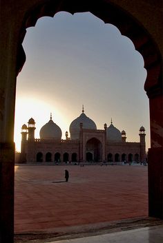 the sun is setting in front of a large building with arches and domes on it