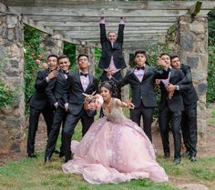 a group of men and women in tuxedos posing for a photo with their hands up