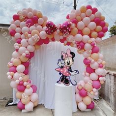 a minnie mouse balloon arch decorated with pink and gold balloons