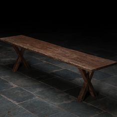 a wooden bench sitting on top of a stone floor