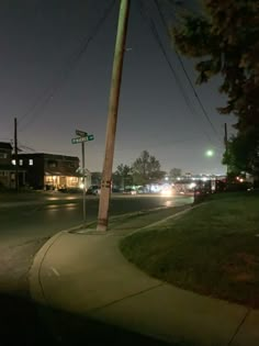 a street corner at night with cars driving on the road