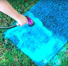 someone using a blow dryer to spray paint on the ground with blue and green grass