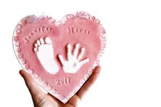 a hand and foot imprint on a heart shaped cake for a baby's first birthday