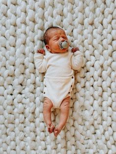 a baby is sleeping on a blanket with a pacifier in its mouth and it's eyes closed