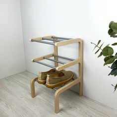 a pair of shoes are on a wooden shoe rack next to a potted plant