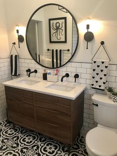 a bathroom with black and white tiles, a mirror, toilet and sink in it