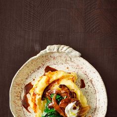 a white plate topped with meat and veggies on top of a wooden table