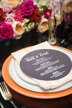 an orange and white plate with a menu on it next to some pink and purple flowers