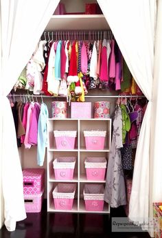 an organized closet with pink bins and white curtains