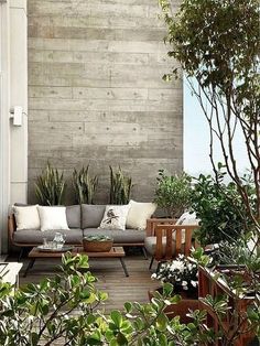 an outdoor living area with couches and potted plants on the side of the house