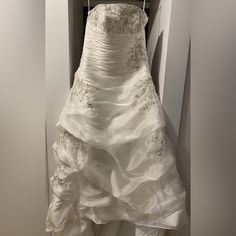 a white wedding dress hanging on a hanger in a closet at the end of a hallway