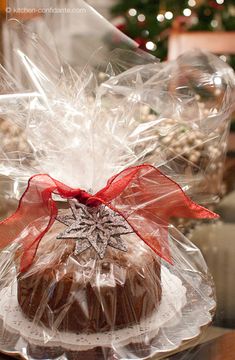 a chocolate cake wrapped in plastic and sitting on a table next to a christmas tree