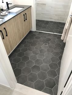 a bathroom with grey hexagonal tiles on the floor, and wooden cabinetry