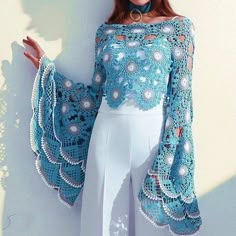 a woman wearing a blue crochet top and white pants with pearls on it