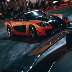 an orange and black sports car parked on the street