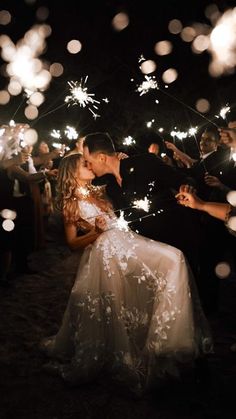 a bride and groom kissing while surrounded by sparklers