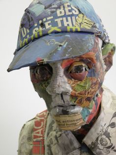 a man wearing a blue hat and covered in paper mache is looking at the camera