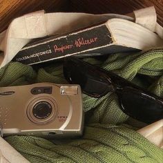 a camera, sunglasses and book on a blanket