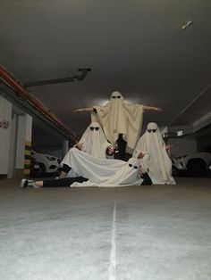 three people dressed in ghost costumes sitting on the ground