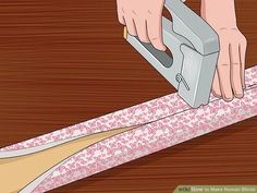 a person using a stapler to cut fabric on a table top with pink and white designs