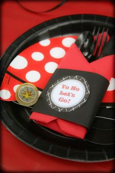 a black and red paper plate with napkins on it, along with a polka dot napkin