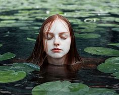 a woman is floating in the water with lily pads