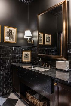 a bathroom with black and white tile, gold trimmings and pictures on the wall