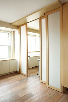 an empty room with wooden floors and sliding doors on the side, in front of a window