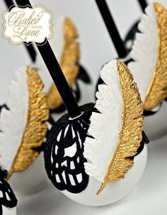 some white and gold decorated eggs sitting on top of each other with black sticks sticking out of them