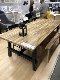 two people are shopping at a furniture store with wooden tables and chairs in the background