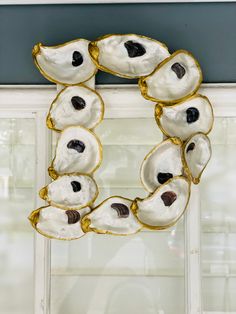 a wreath made out of white and gold seashells on a window sill