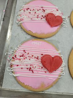 three heart shaped cookies sitting on top of a cookie sheet