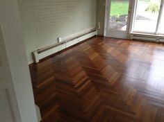 an empty room with hard wood floors and large windows