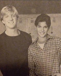 two people standing next to each other in an old black and white photo with one person smiling at the camera