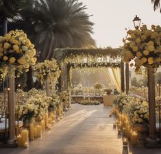 an outdoor wedding setup with yellow flowers and candles on the aisle, surrounded by palm trees