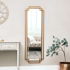 a mirror sitting on top of a white table next to a vase with a plant