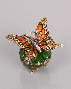 a butterfly brooch sitting on top of a green vase