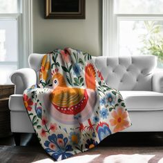 a white couch sitting next to a window covered in a colorful bird blanket