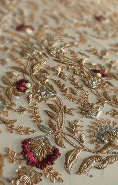 an embroidered fabric with gold and red flowers on it