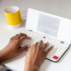 a person typing on a white laptop computer