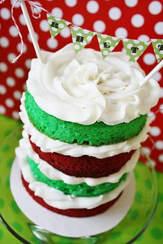 a cake with white frosting and green icing on a glass plate in front of a polka dot tablecloth