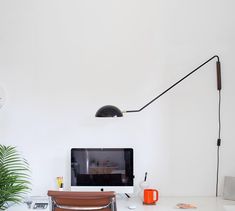 a desk with a monitor, keyboard and chair in front of the wall mounted television