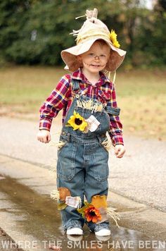 a small child wearing overalls and a hat with sunflowers on it's head