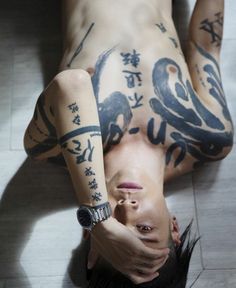 a man with tattoos on his body laying down