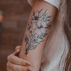 a woman's arm with flowers and leaves tattooed on the left side of her arm