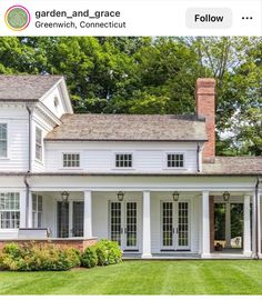 a large white house sitting on top of a lush green field in front of trees